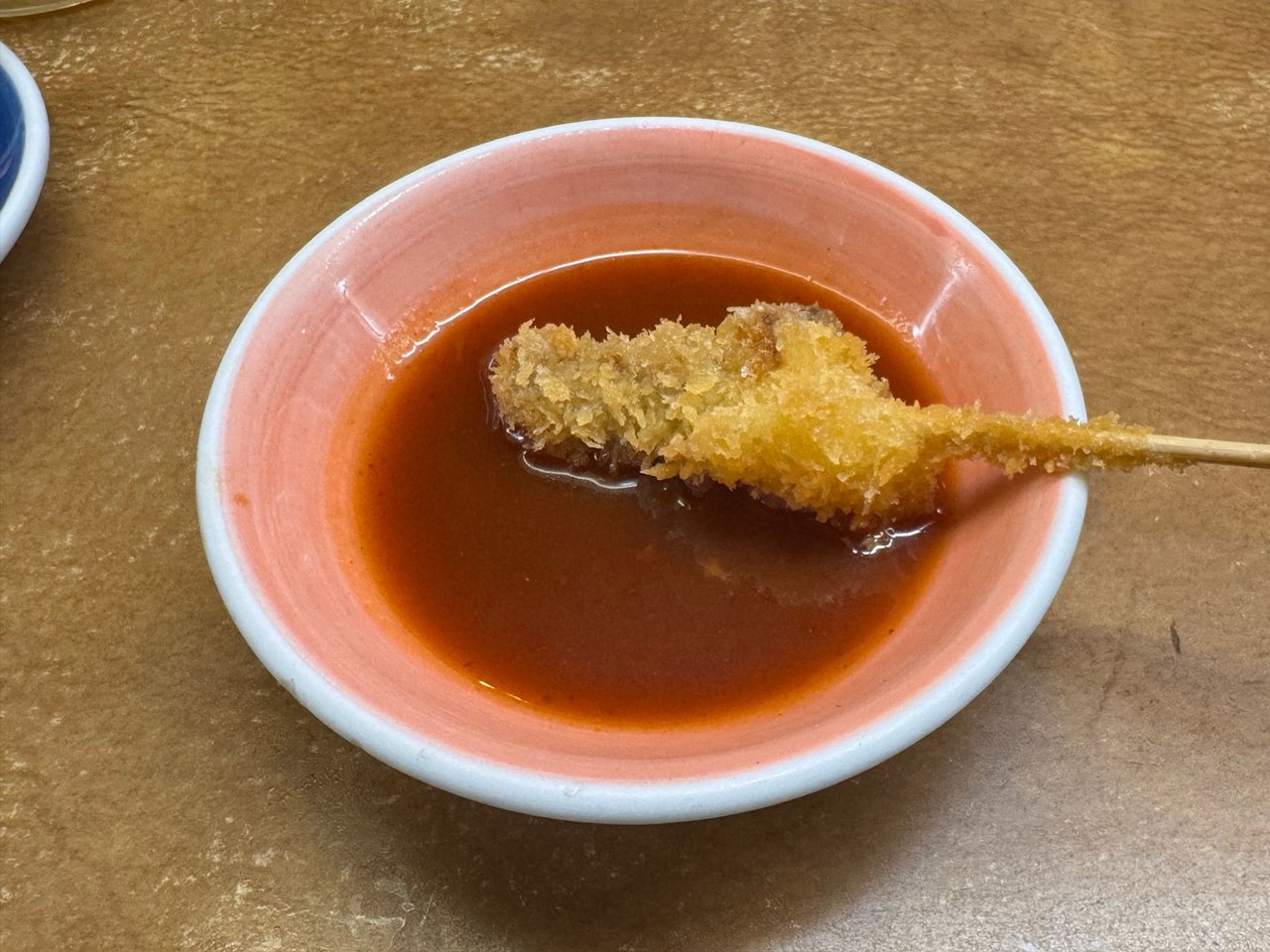 やきとりの名門 秋吉 総曲輪店 串カツをタレにつけたところ