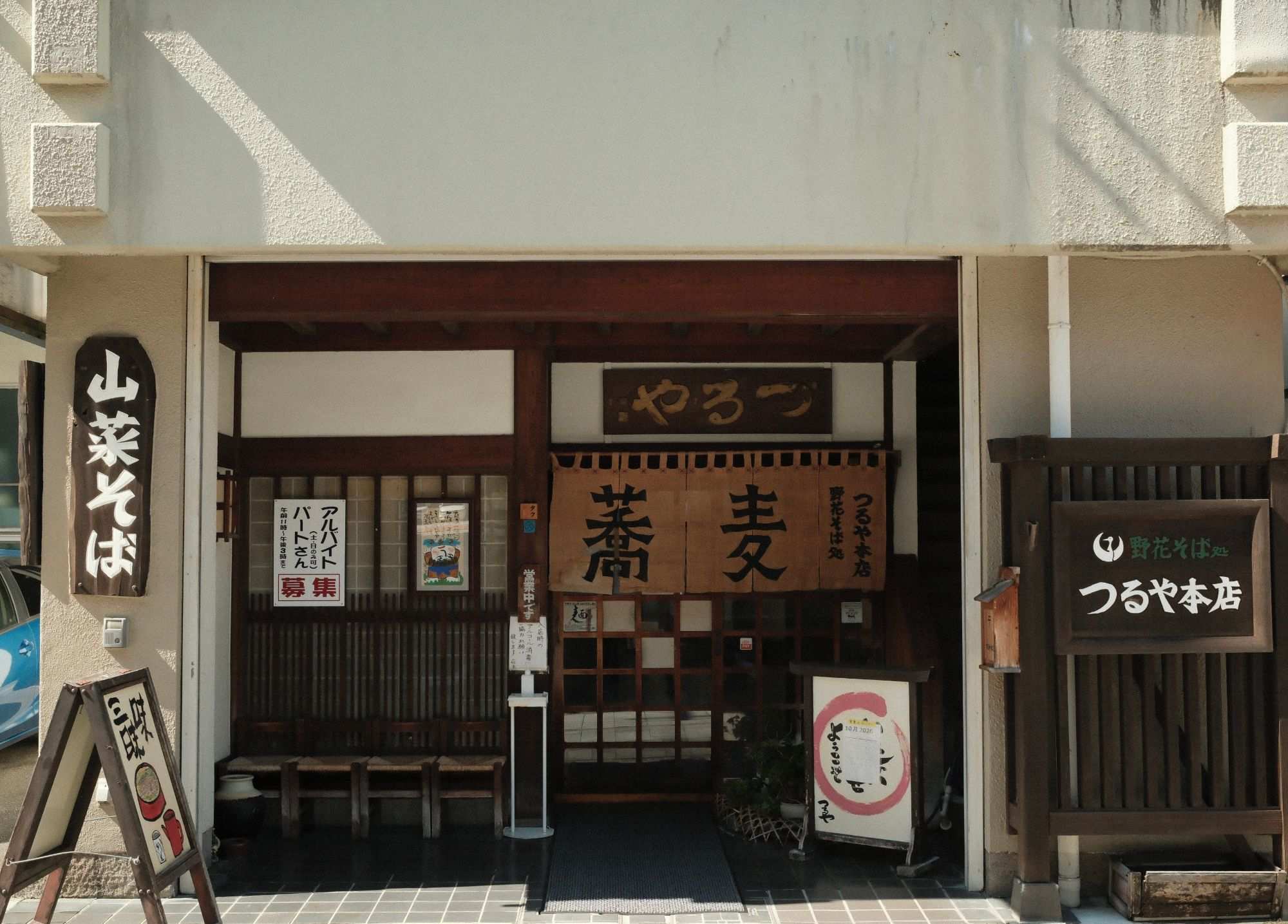 野花そば処 つるや本店 店の正面（蕎麦の暖簾と山菜そばの看板）